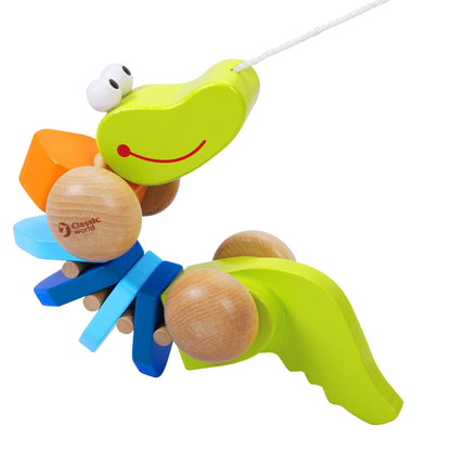 Close-up of segmented crocodile toy suspended mid-air, showing its curved wooden body, wheels, and cheerful face with a red smile.