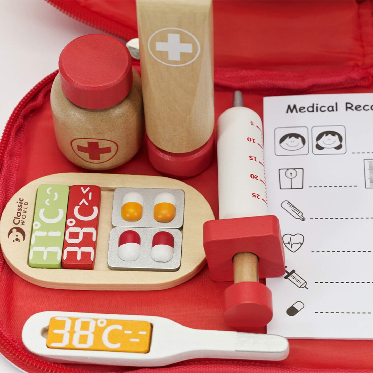 Wooden medical play pieces including syringe, cream tube and medicine bottle placed inside a red fabric case.