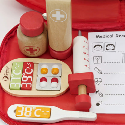 Wooden medical play pieces including syringe, cream tube and medicine bottle placed inside a red fabric case.