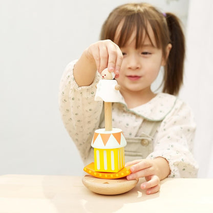 A child playing with a stacking and balancing Clown themed toy, carefully assembling colourful wooden blocks and the clown figure.