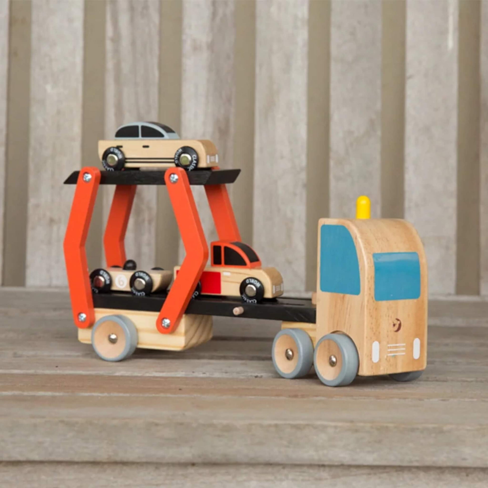 Wooden toy car transporter with adjustable ramp, holding three small toy cars on two levels.