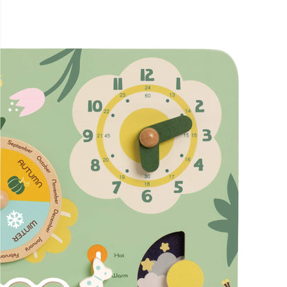 Close-up of a flower-shaped wooden clock with green hands and 12- and 24-hour markings in soft pastel tones.