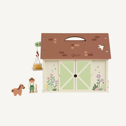 Closed wooden toy barn with green doors, carry handle roof and illustrated farm details for pretend play.