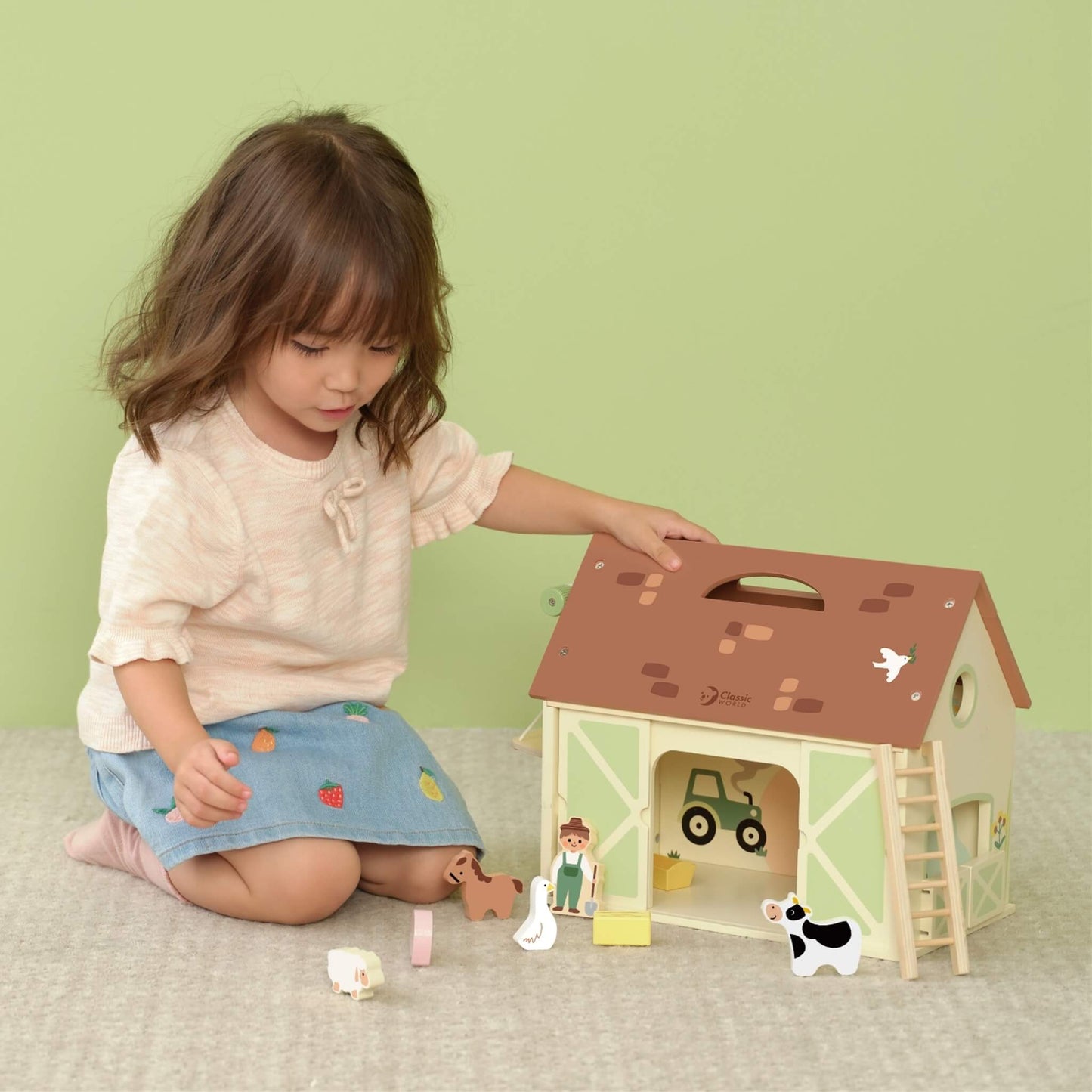 Child playing with wooden farm playset and animal figures including cow, pig, sheep and farmer.