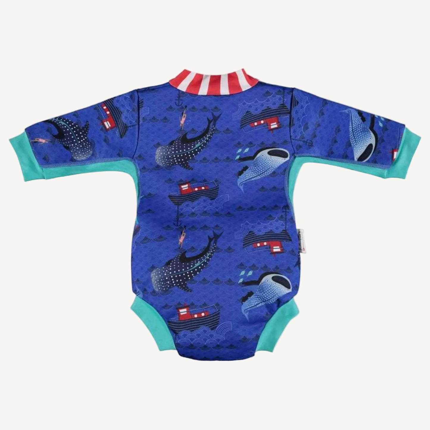 A baby cosy suit shown from the back with long sleeves, teal cuffs and a blue ocean-themed whale shark print featuring boats and waves.