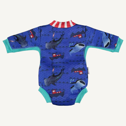 A baby cosy suit shown from the back with long sleeves, teal cuffs and a blue ocean-themed whale shark print featuring boats and waves.
