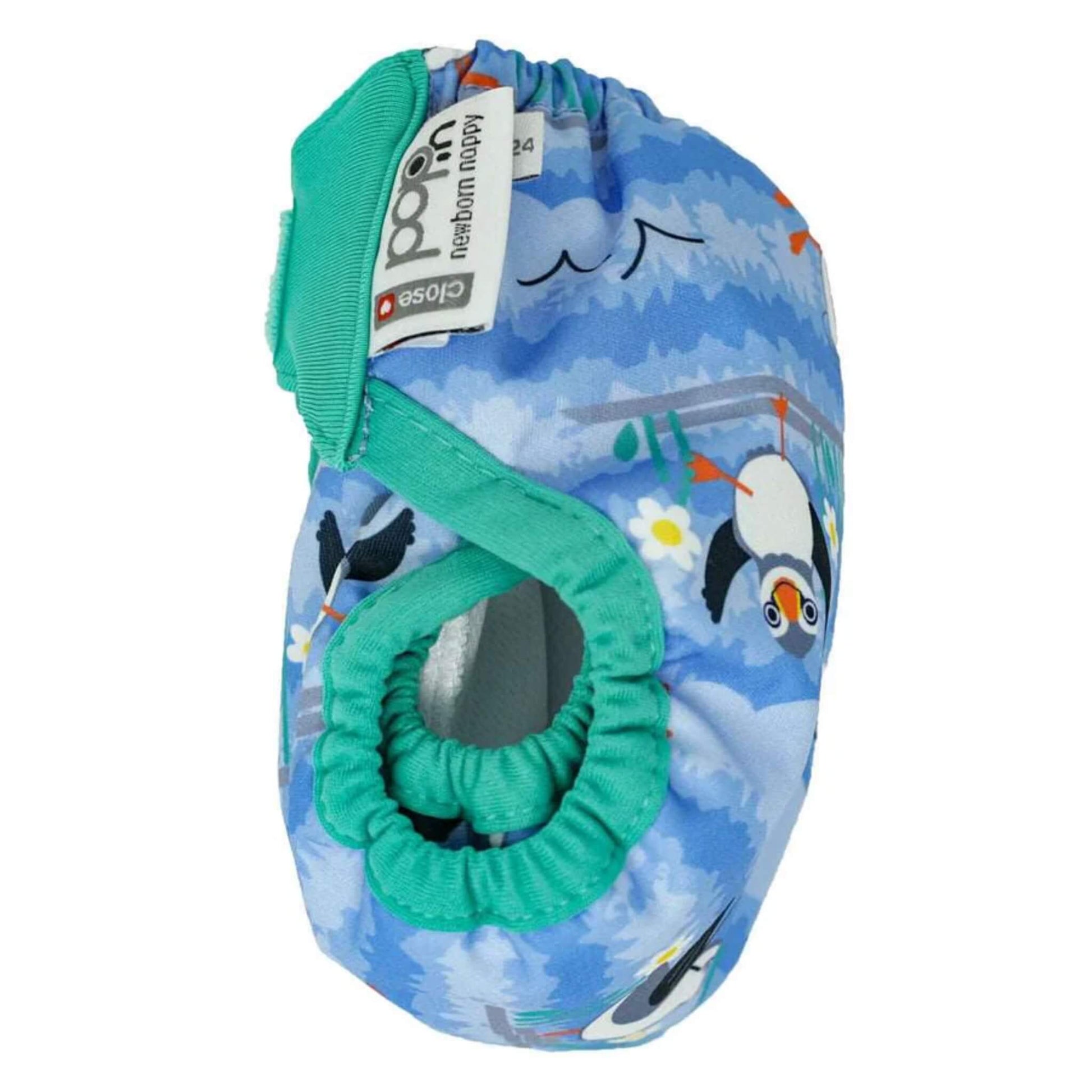 A newborn reusable nappy photographed from the side with teal leg elastic and a blue puffin print across the outer shell.