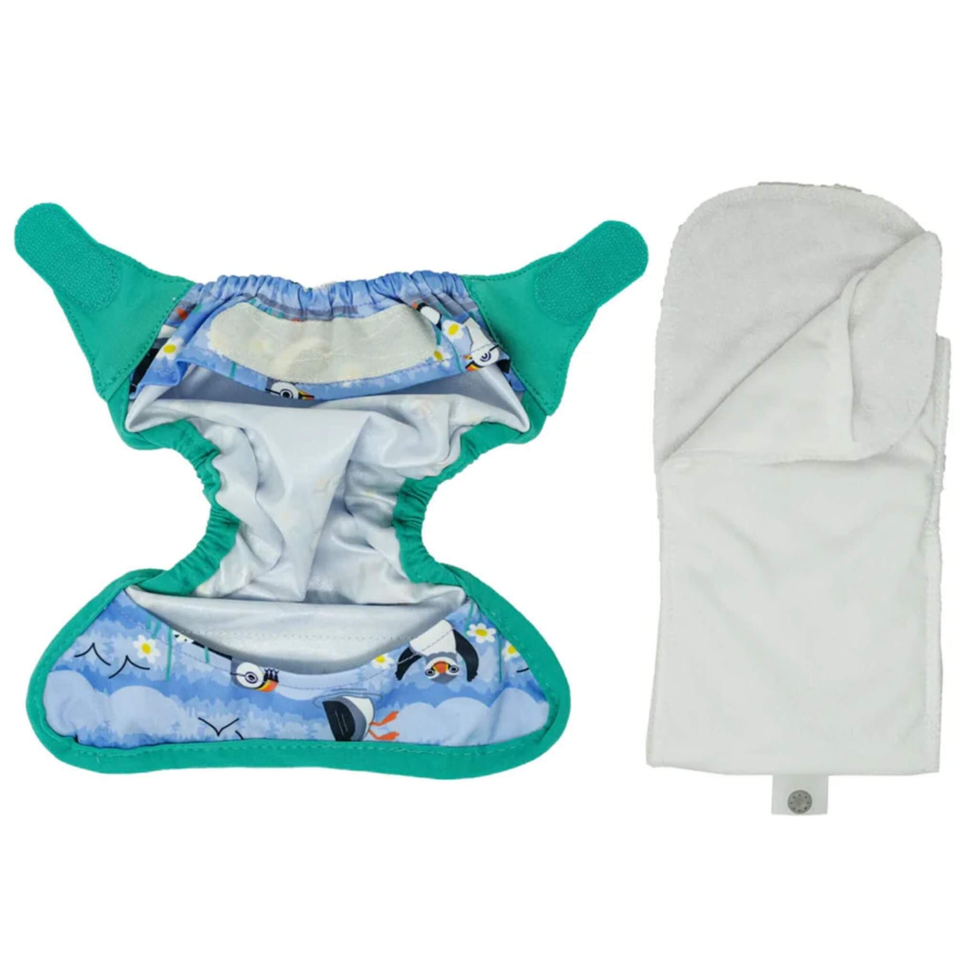 A newborn reusable nappy shown open with the absorbent soaker laid separately beside the printed outer wrap.