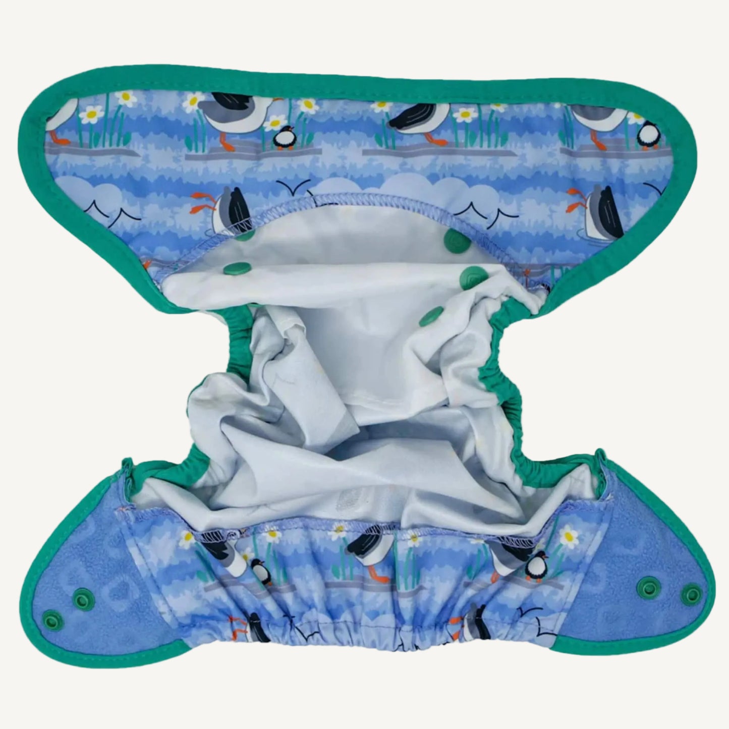A reusable nappy cover laid open to show the inside, with elasticated leg openings, light inner fabric, and popper tabs along the waistband and wings.