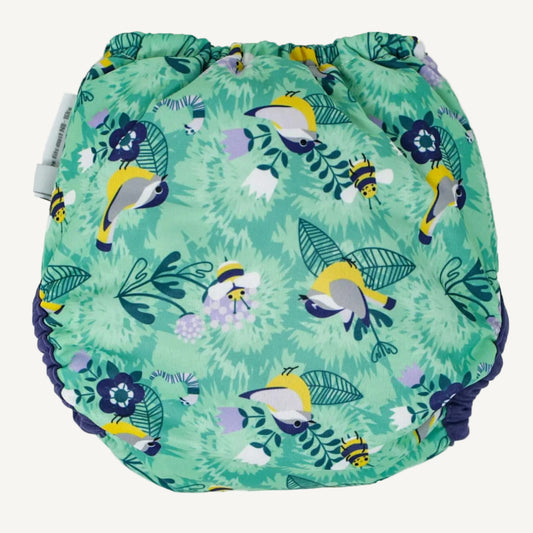 A reusable nappy cover laid flat on its back showing a green patterned fabric with small birds, bees and leaves.