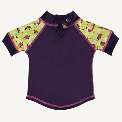 A short-sleeved rash vest shown from the back with a purple body, patterned yellow-and-pink sleeves and a single popper fastening at the neck.