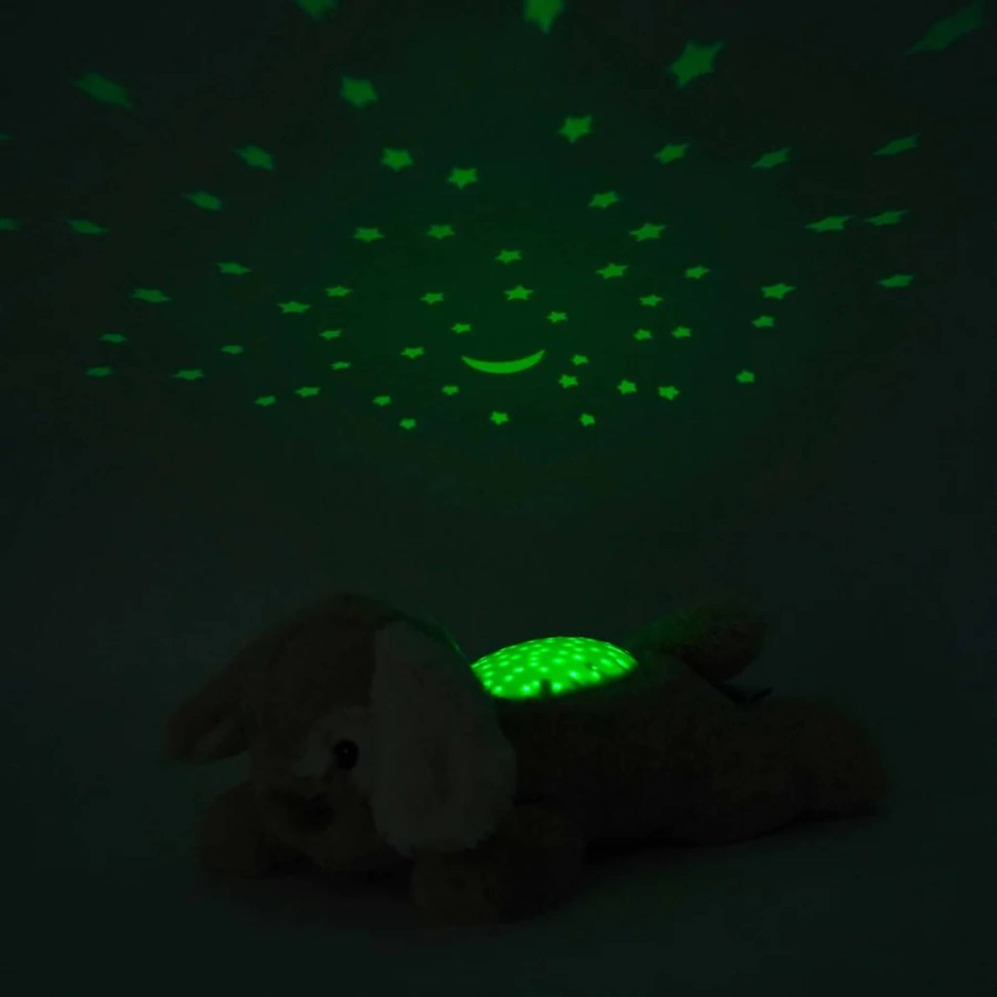Plush puppy toy lying in a dark room with its night-light projecting glowing green stars and a crescent moon across the ceiling.