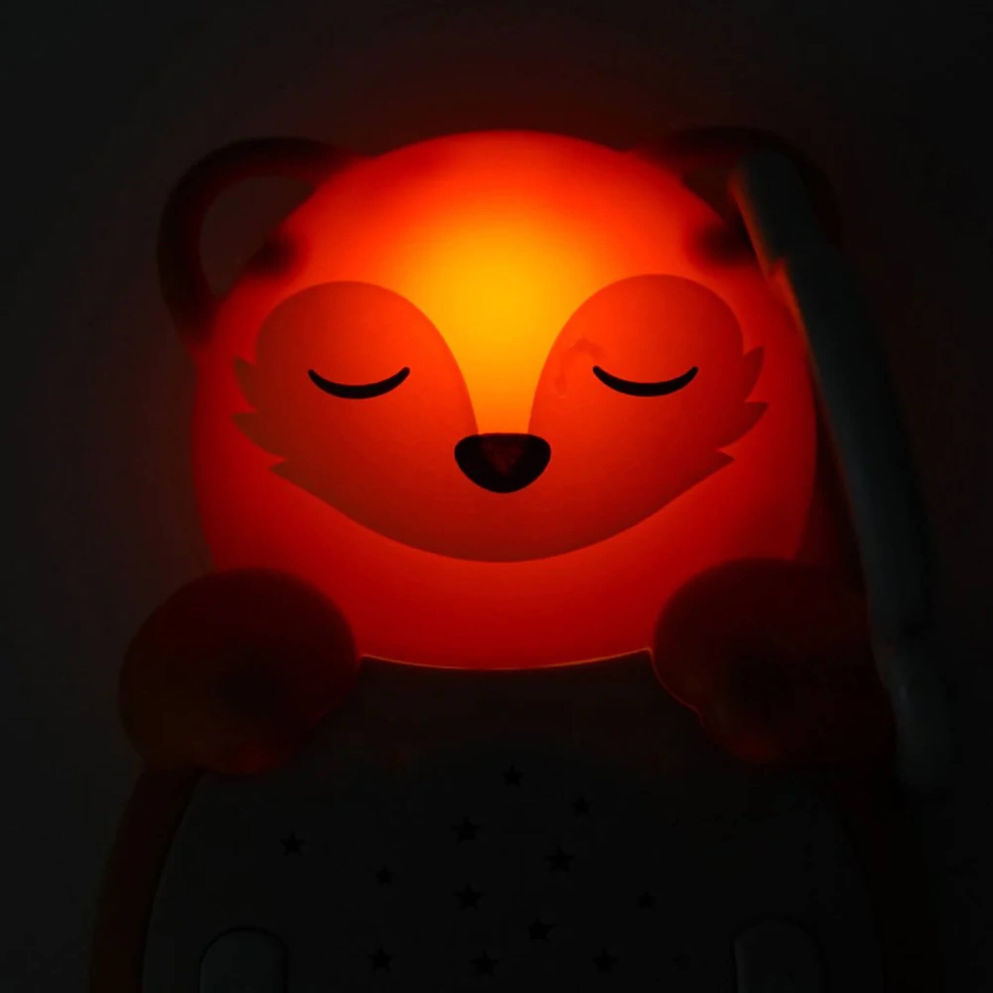 Close-up of a fox night-light glowing red in the dark, its face softly illuminated with closed eyes for a calming effect at bedtime.