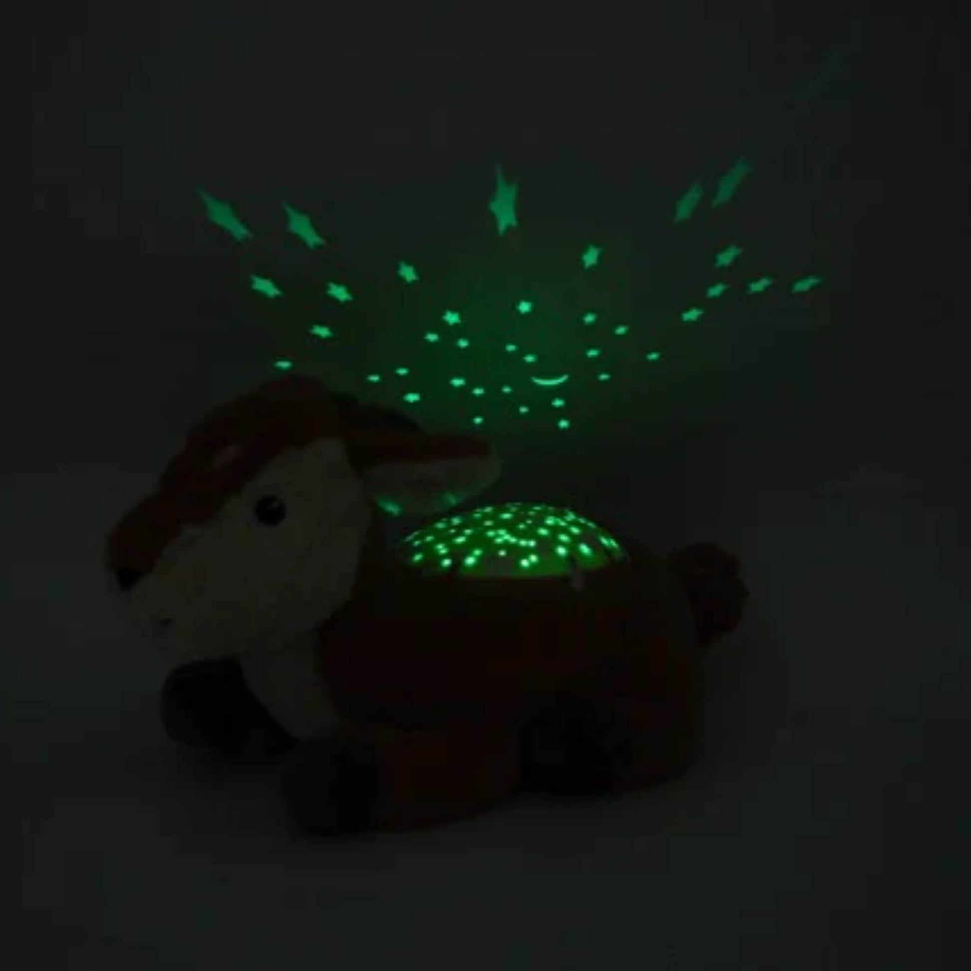 A fawn night light in a dark room projecting green stars, a crescent moon and constellation shapes upwards onto the ceiling and nearby wall.