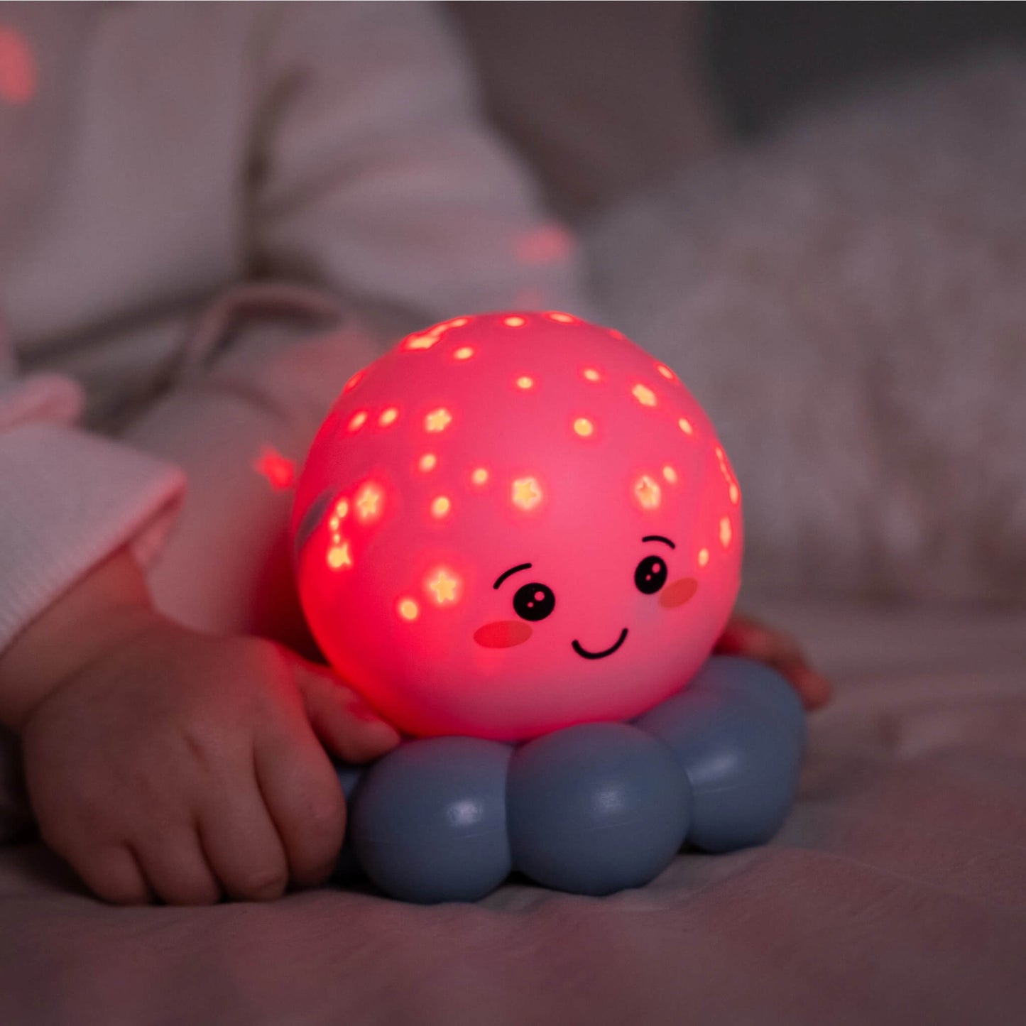 A glowing red octopus night light beside a child in bed.