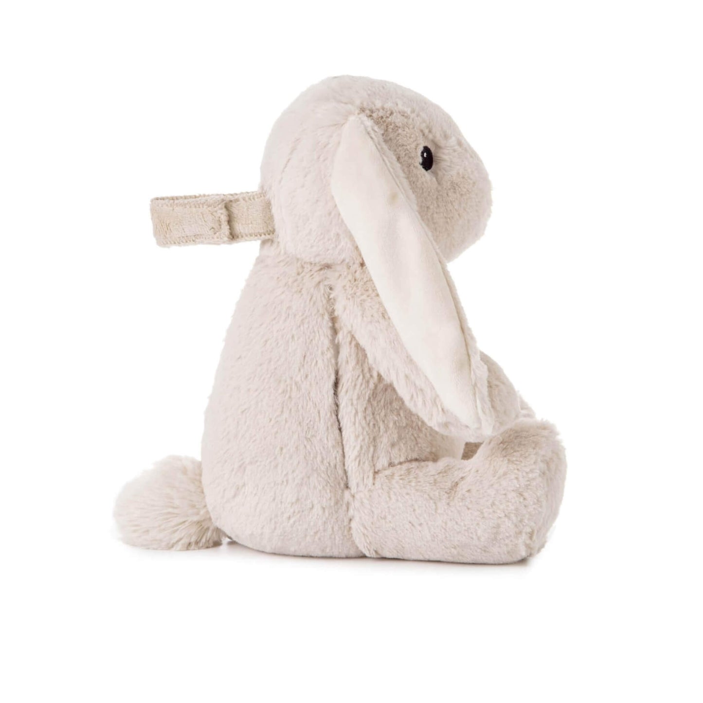 Side profile of a soft bunny toy with floppy ears, short tail and a fabric strap attached to its back.