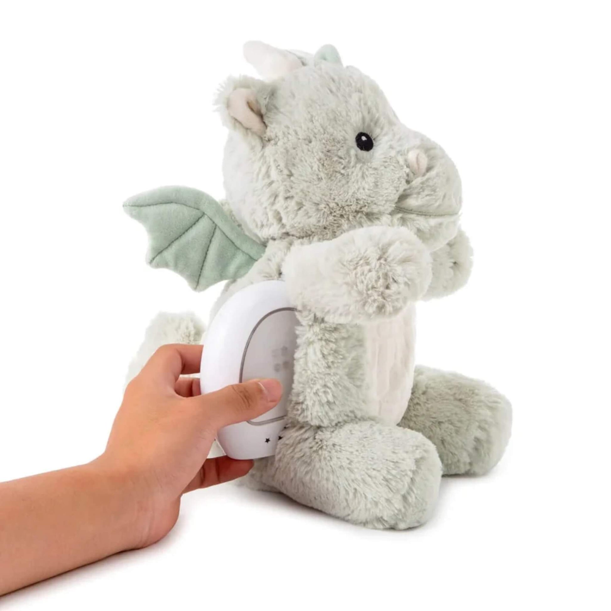 A hand is shown inserting the small white nightlight unit into the back of the plush dragon toy.