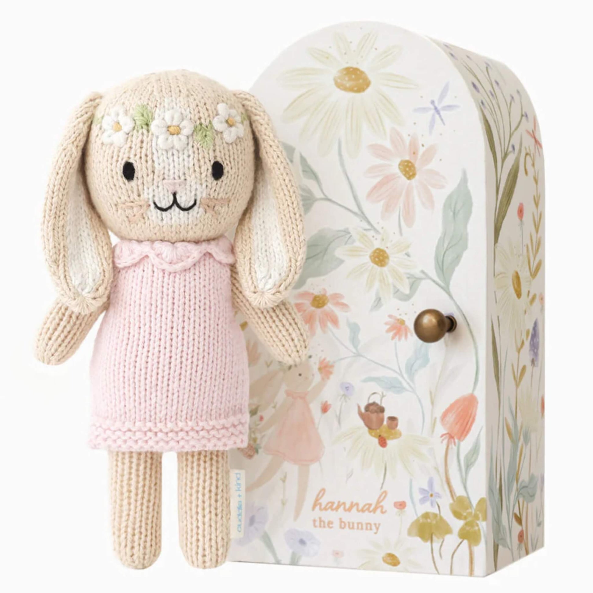Cuddle + Kind Tiny Collection Hannah the Bunny knitted soft toy in pink dress with floral gift box beside.