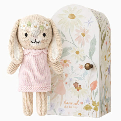 Cuddle + Kind Tiny Collection Hannah the Bunny knitted soft toy in pink dress with floral gift box beside.