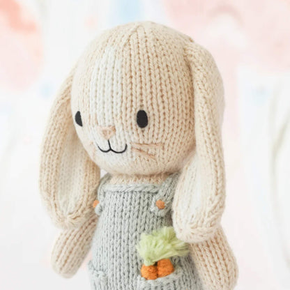 Close-up of knitted bunny face with stitched eyes, soft cream yarn texture and gentle facial detailing.