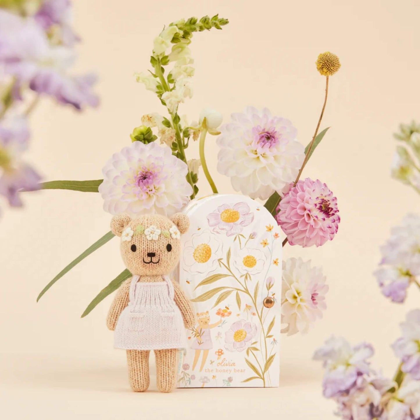 A hand-knit doll standing beside a decorative keepsake box with hand-painted flowers in soft pastel tones.