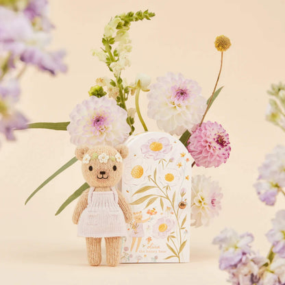 A hand-knit doll standing beside a decorative keepsake box with hand-painted flowers in soft pastel tones.