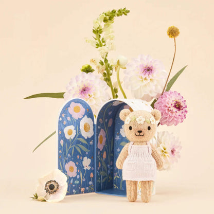 An illustrated Tiny home box opened to reveal a deep blue night scene with floral details and a knitted doll placed in front.