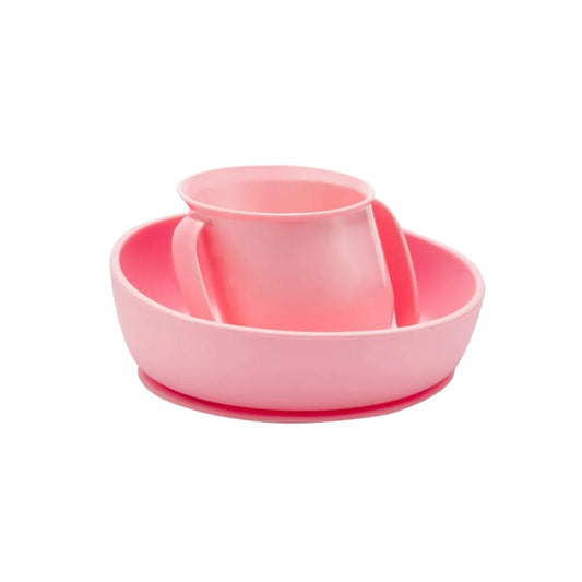 A pink Doidy Cup and Bowl displayed together, featuring the brand’s signature slanted designs to support independent feeding and reduce spills for babies and toddlers.