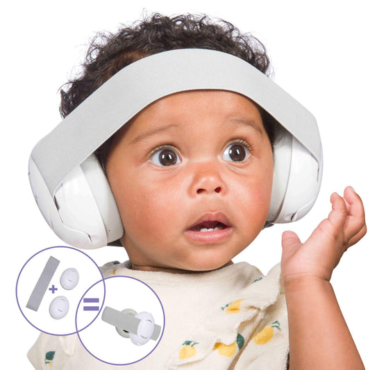 A baby wearing white ear defenders secured with a wide grey headband, shown close-up with a surprised expression and ears fully covered.