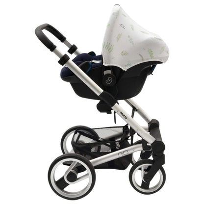 A white car seat hoody with green leafy design attached to an infant car seat placed on a silver pushchair frame, showing compatibility with a travel system.