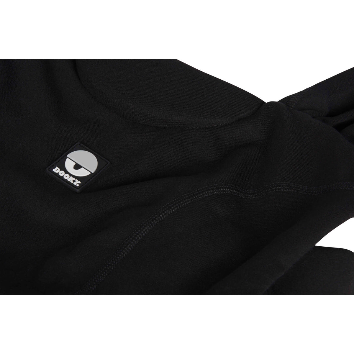A close-up of the black baby carrier fabric, stitched front panel and padded upper edge with logo detail.