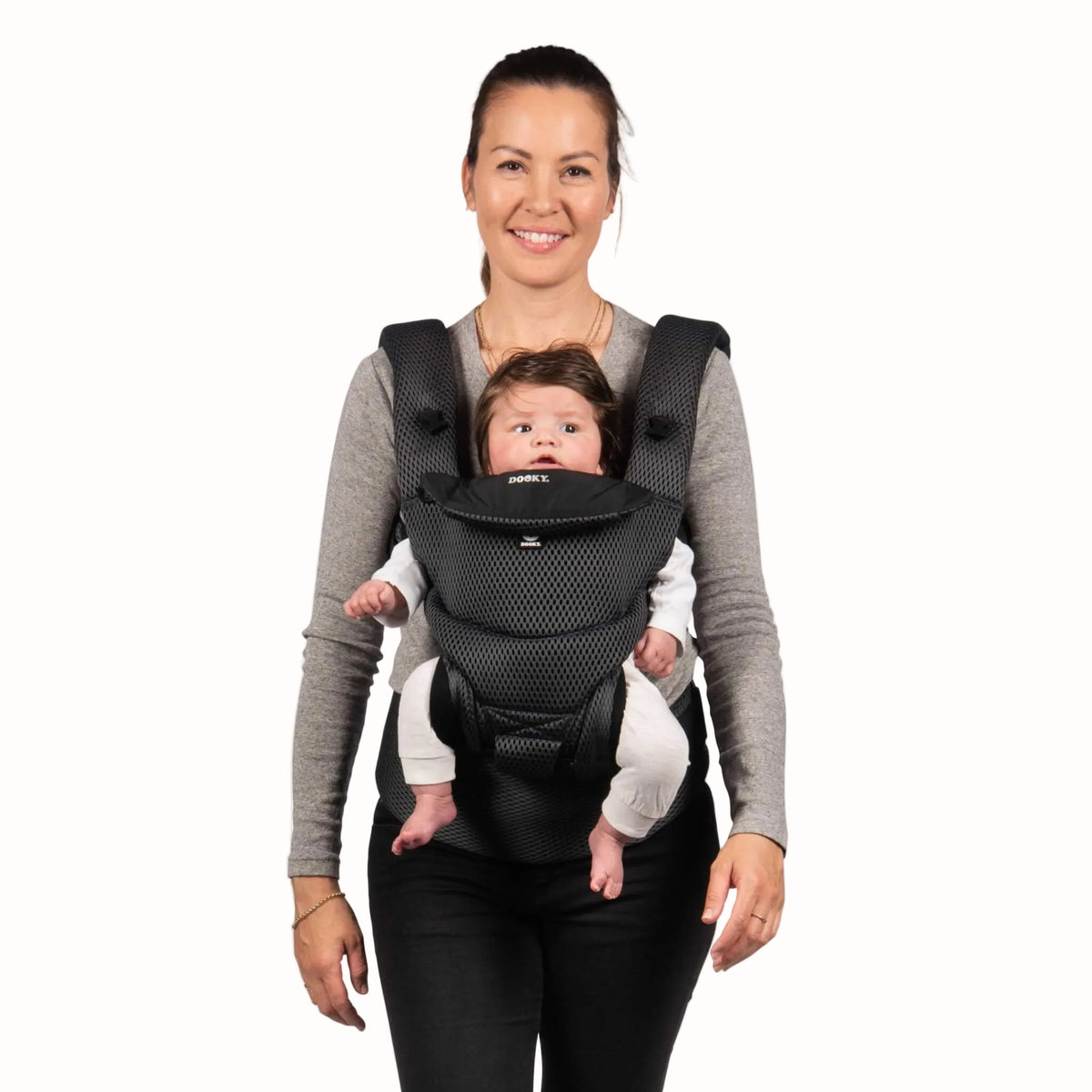 A woman wearing a grey mesh baby carrier with a young baby supported in a front-facing inward position.