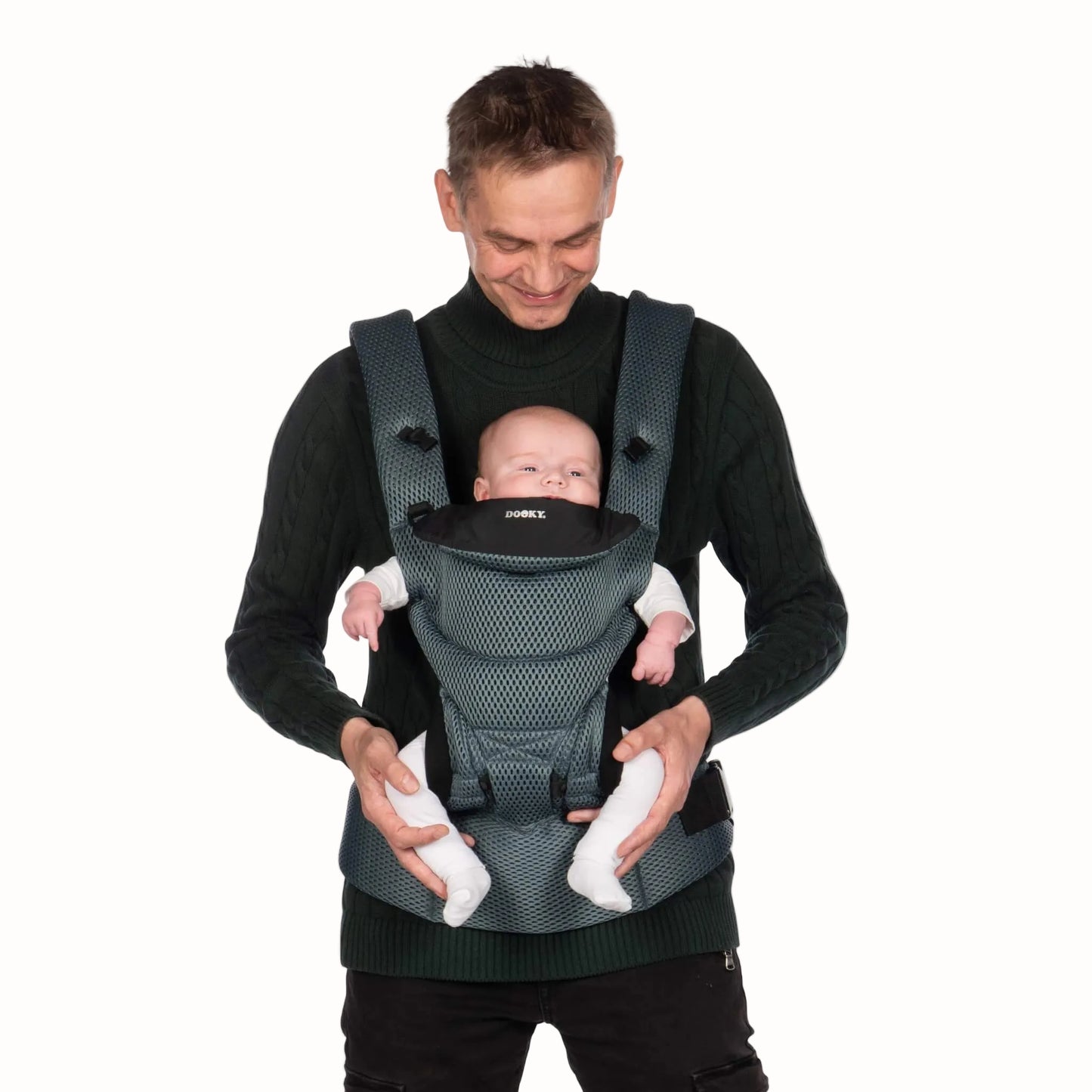 A man wearing a grey mesh baby carrier with a young baby supported against his chest in a front-facing inward position.