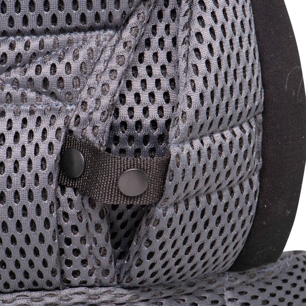Close-up of a press-stud fastening on a grey mesh baby carrier.