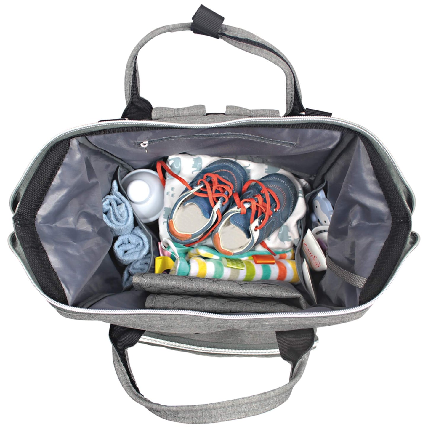 A packed changing bag photographed from above, containing baby shoes, rolled towels, nappies, wipes, and various small baby items.
