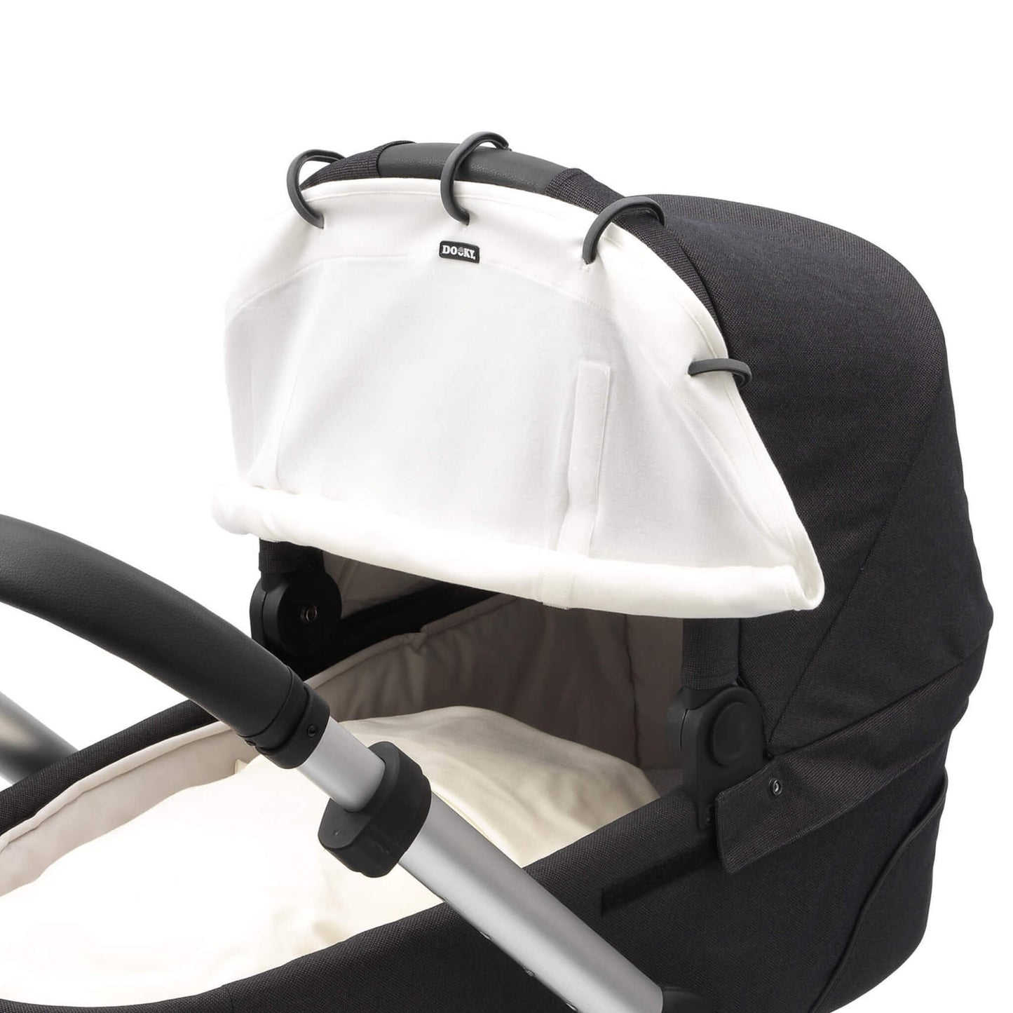 Close-up of a cream sunshade attached to a pram hood using five black plastic rings. Two vertical Velcro strips are visible beside the central logo.