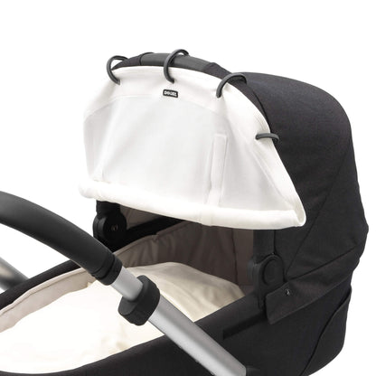 Close-up of a cream sunshade attached to a pram hood using five black plastic rings. Two vertical Velcro strips are visible beside the central logo.