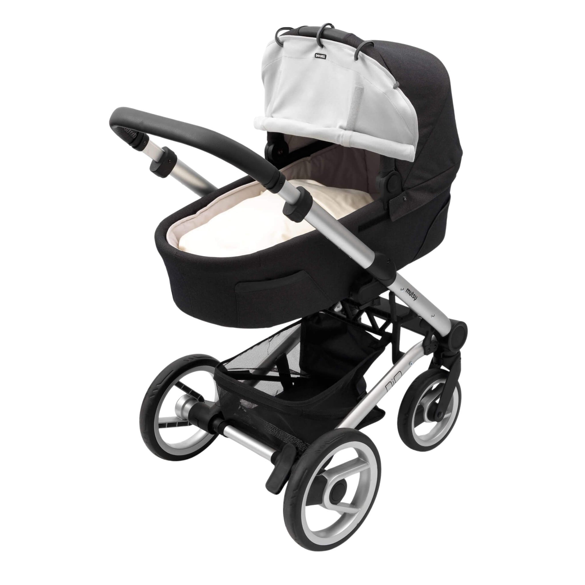 A carrycot pram with a grey sunshade partially rolled up and clipped to the hood using black plastic rings. The pram has a black base and silver frame.