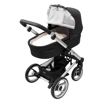 A carrycot pram with a grey sunshade partially rolled up and clipped to the hood using black plastic rings. The pram has a black base and silver frame.