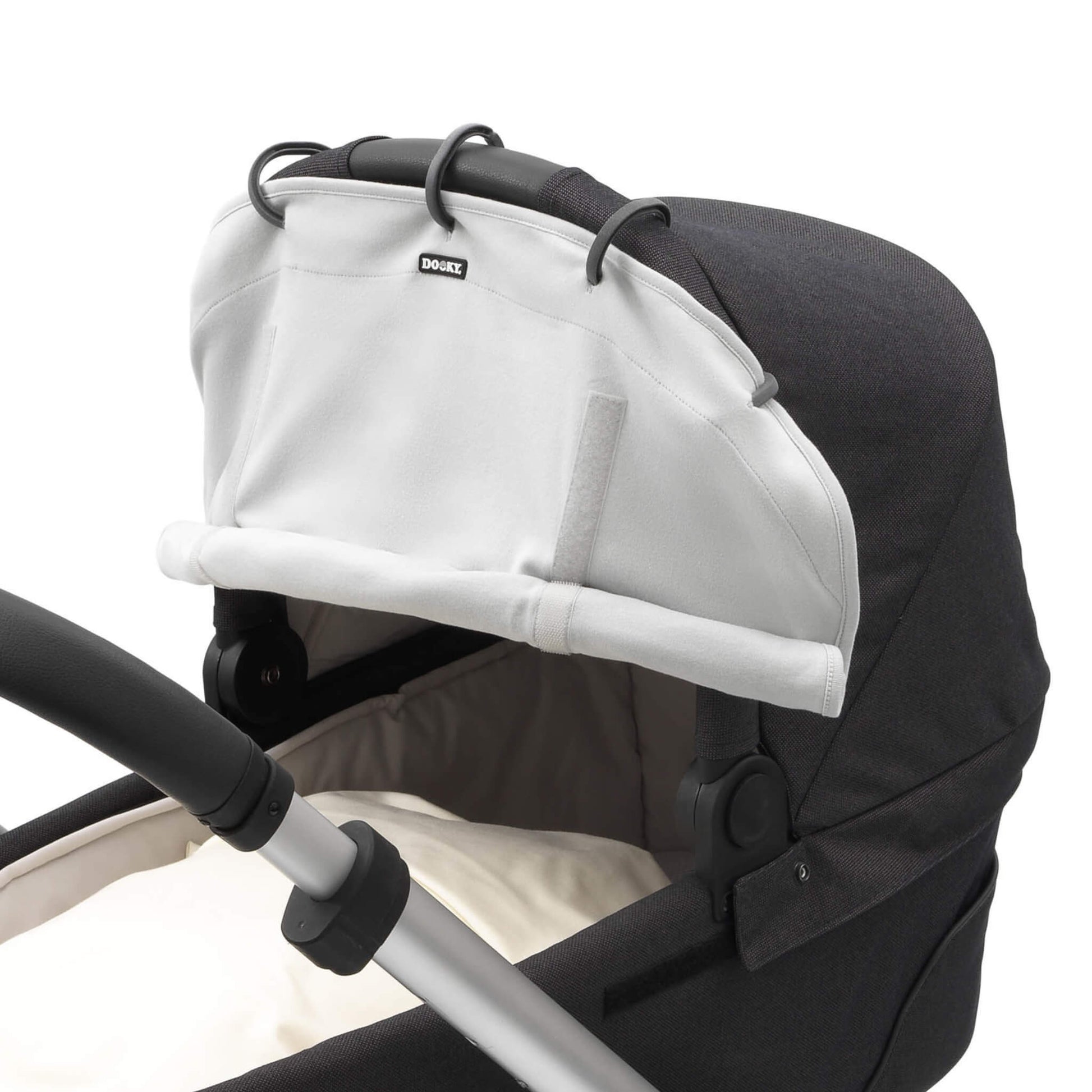 Close-up side view of a grey sunshade fixed to a pram hood using black rings. The shade is partly rolled and held with Velcro.