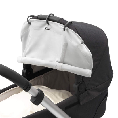 Close-up side view of a grey sunshade fixed to a pram hood using black rings. The shade is partly rolled and held with Velcro.