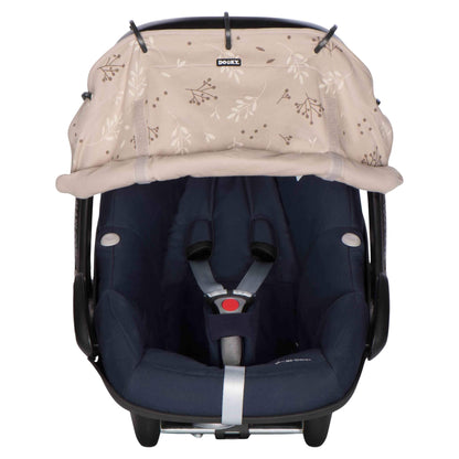 A beige leaf-print sunshade attached to a navy blue infant car seat, partially rolled up to reveal the harness area.