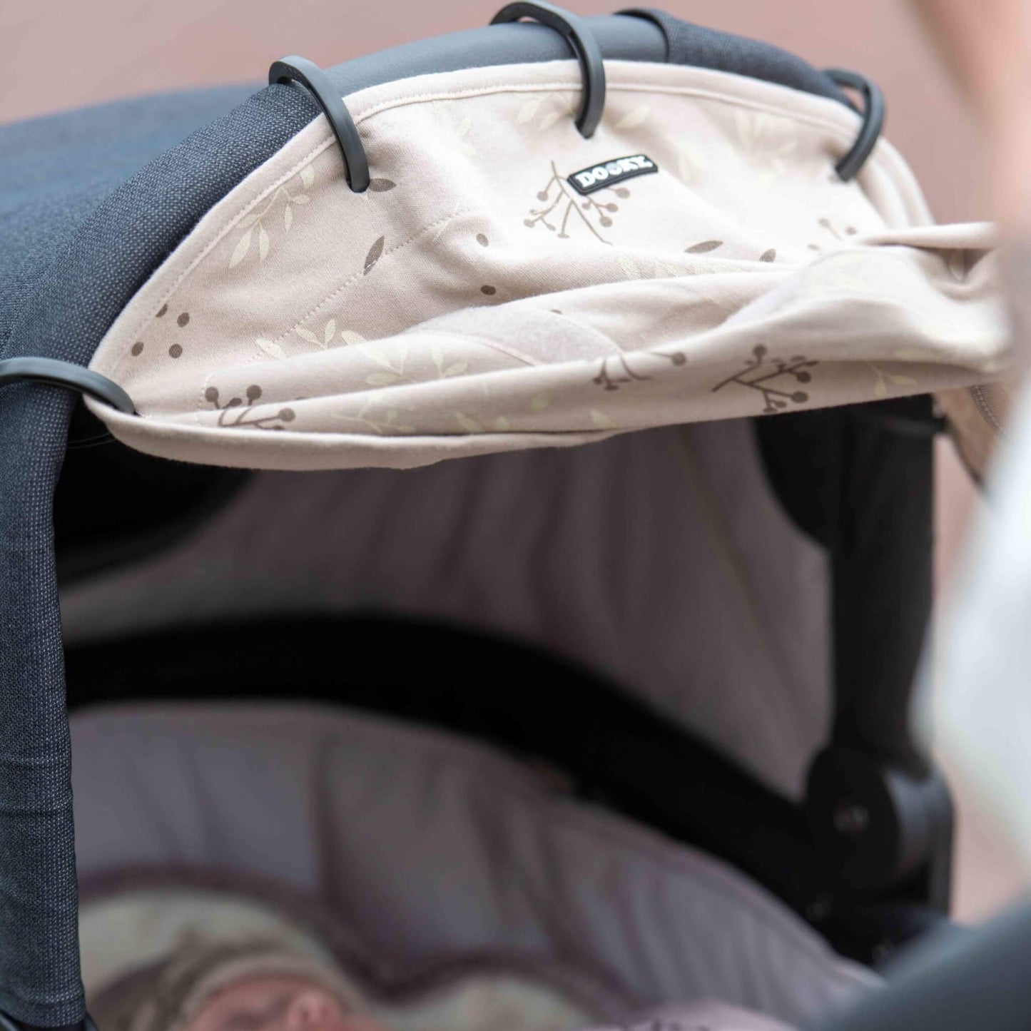 Close-up of a folded sunshade on a stroller canopy, viewed from above a sleeping baby inside the carrycot.