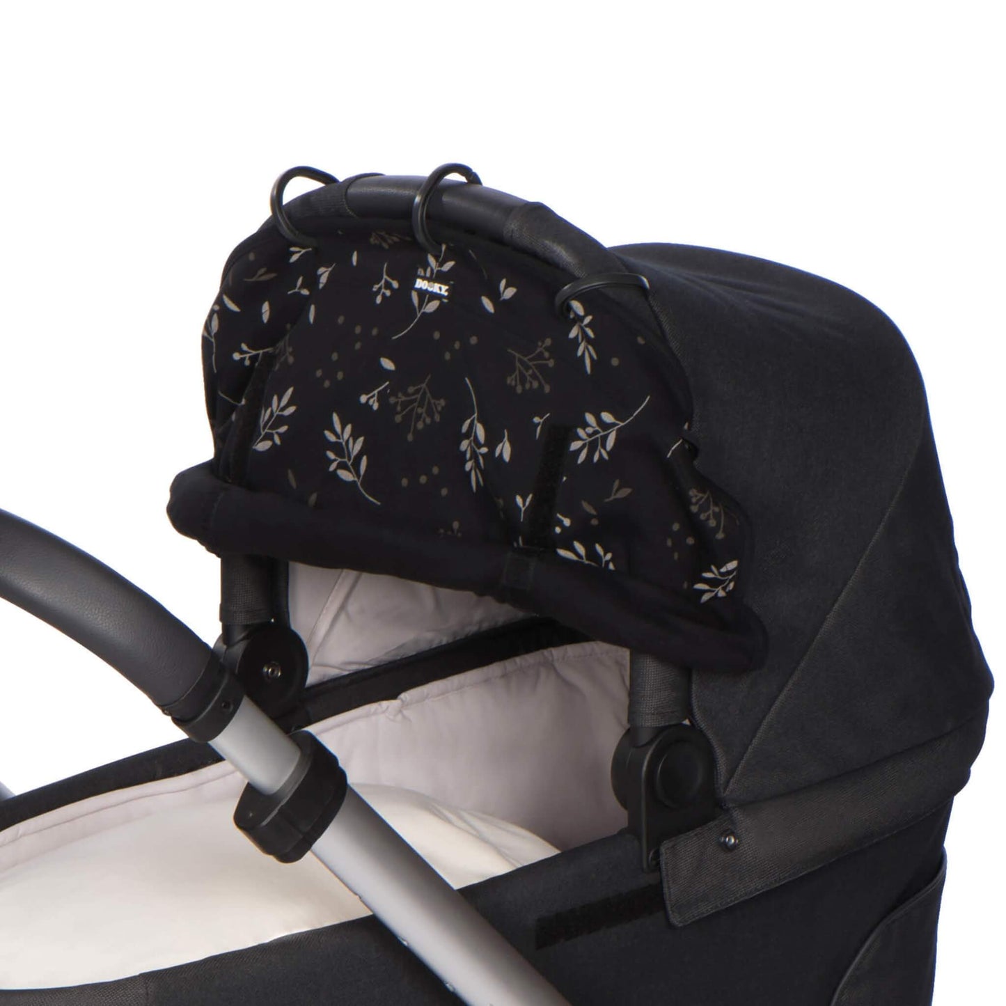 Close-up of the black leaf-patterned sunshade gathered at the top of a pram carrycot, with its five attachment rings clipped onto the hood frame.