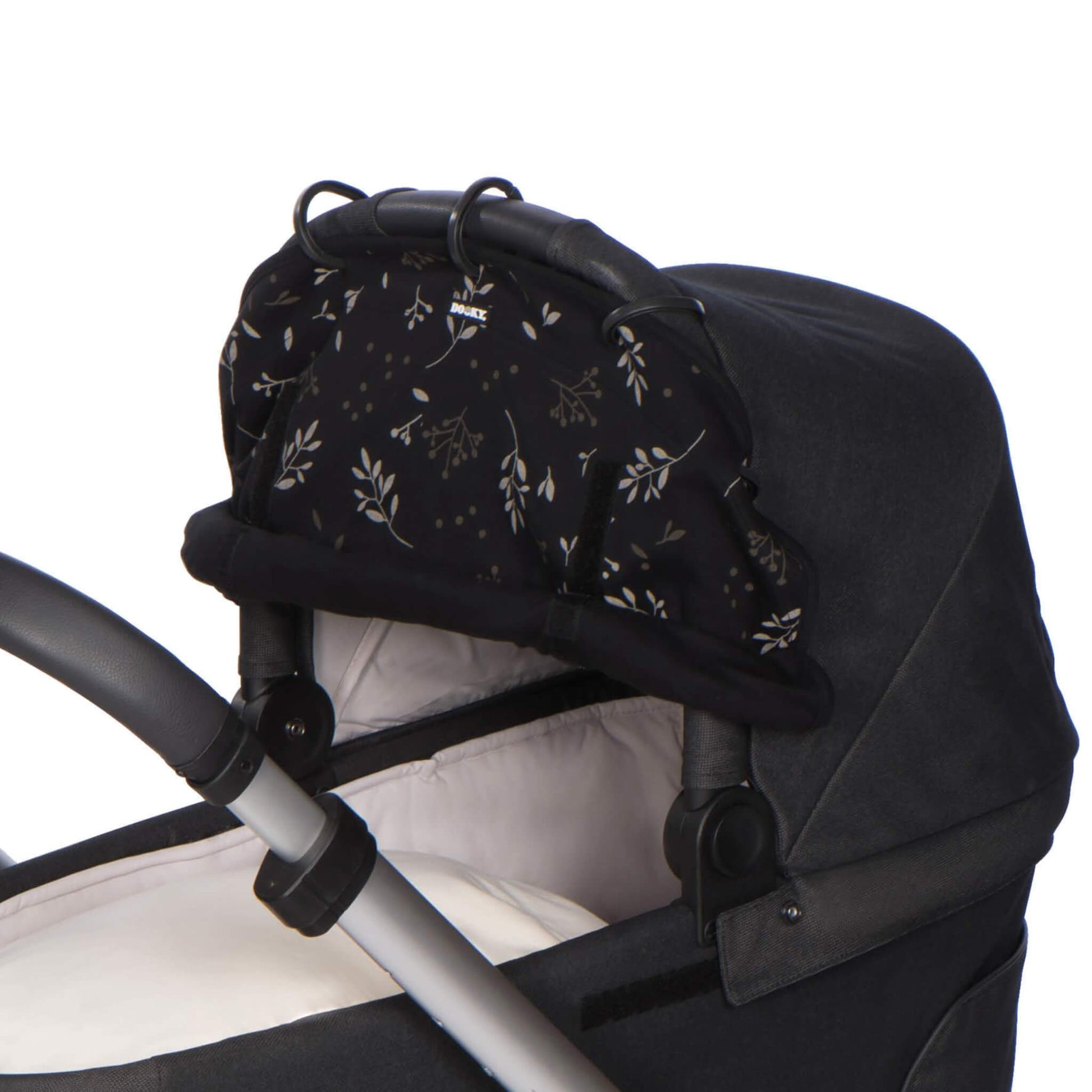 Close-up of the black leaf-patterned sunshade gathered at the top of a pram carrycot, with its five attachment rings clipped onto the hood frame.