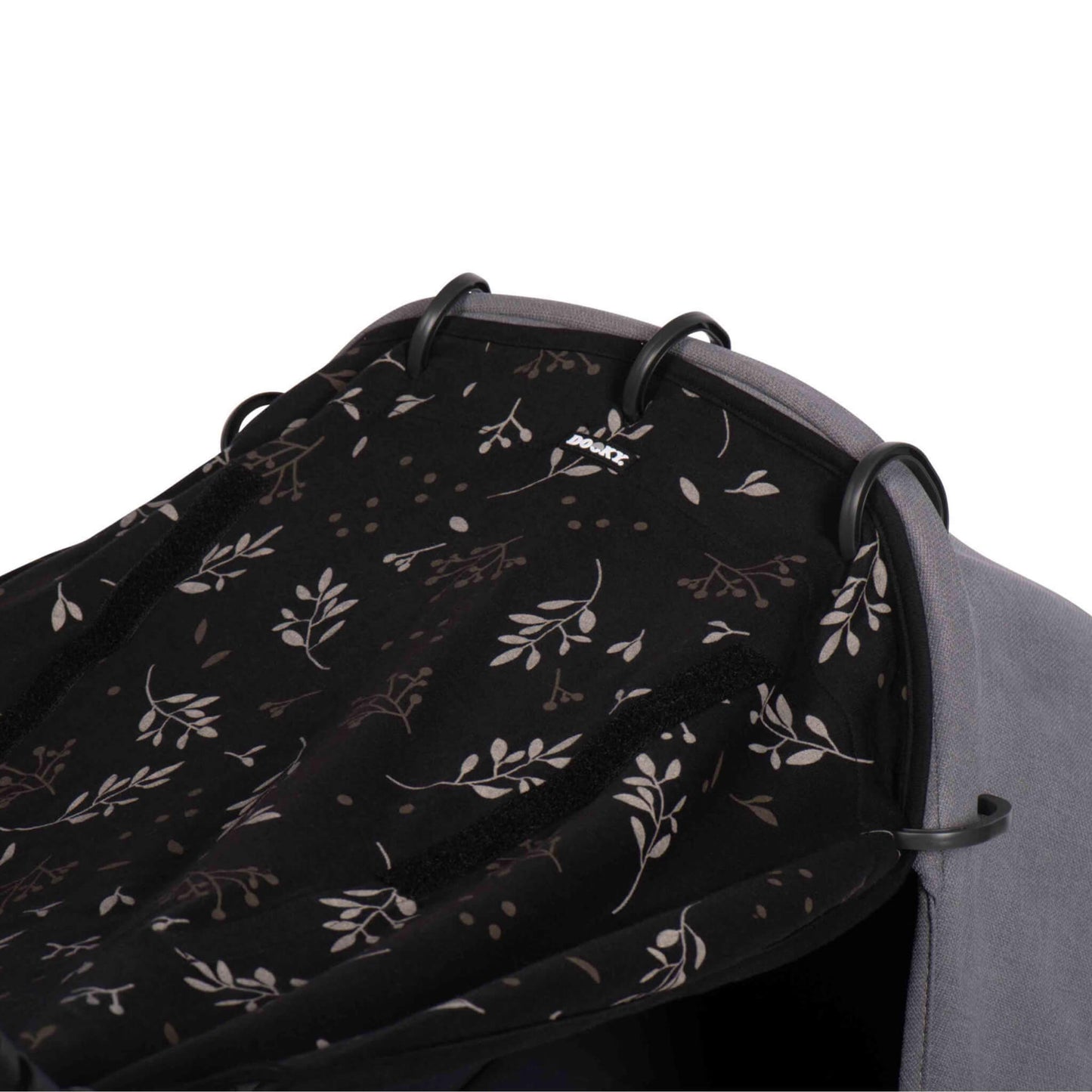 A detailed view of the black sunshade in leaf print pulled taut over the hood of a stroller, showing the fabric texture and ring attachments up close.