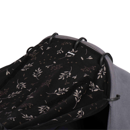 A detailed view of the black sunshade in leaf print pulled taut over the hood of a stroller, showing the fabric texture and ring attachments up close.