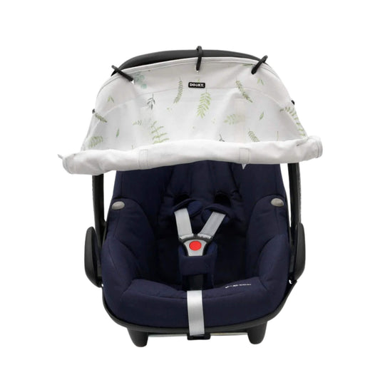 A white leaf-print sunshade attached to the canopy handle of a navy infant car seat, rolled halfway down and secured with Velcro.