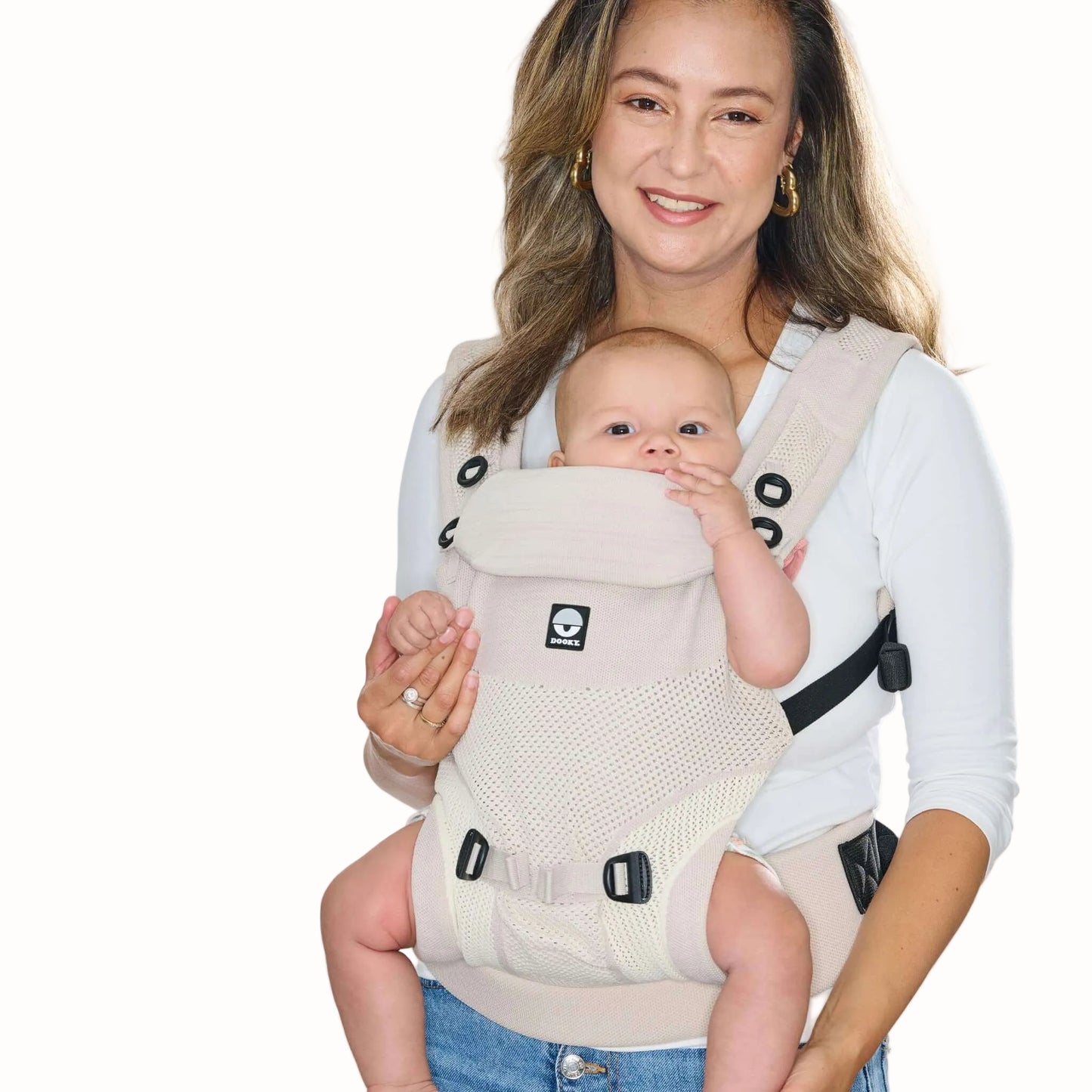 A baby carried facing outwards in a beige baby carrier, showing the supportive seat, shoulder straps and waist belt.