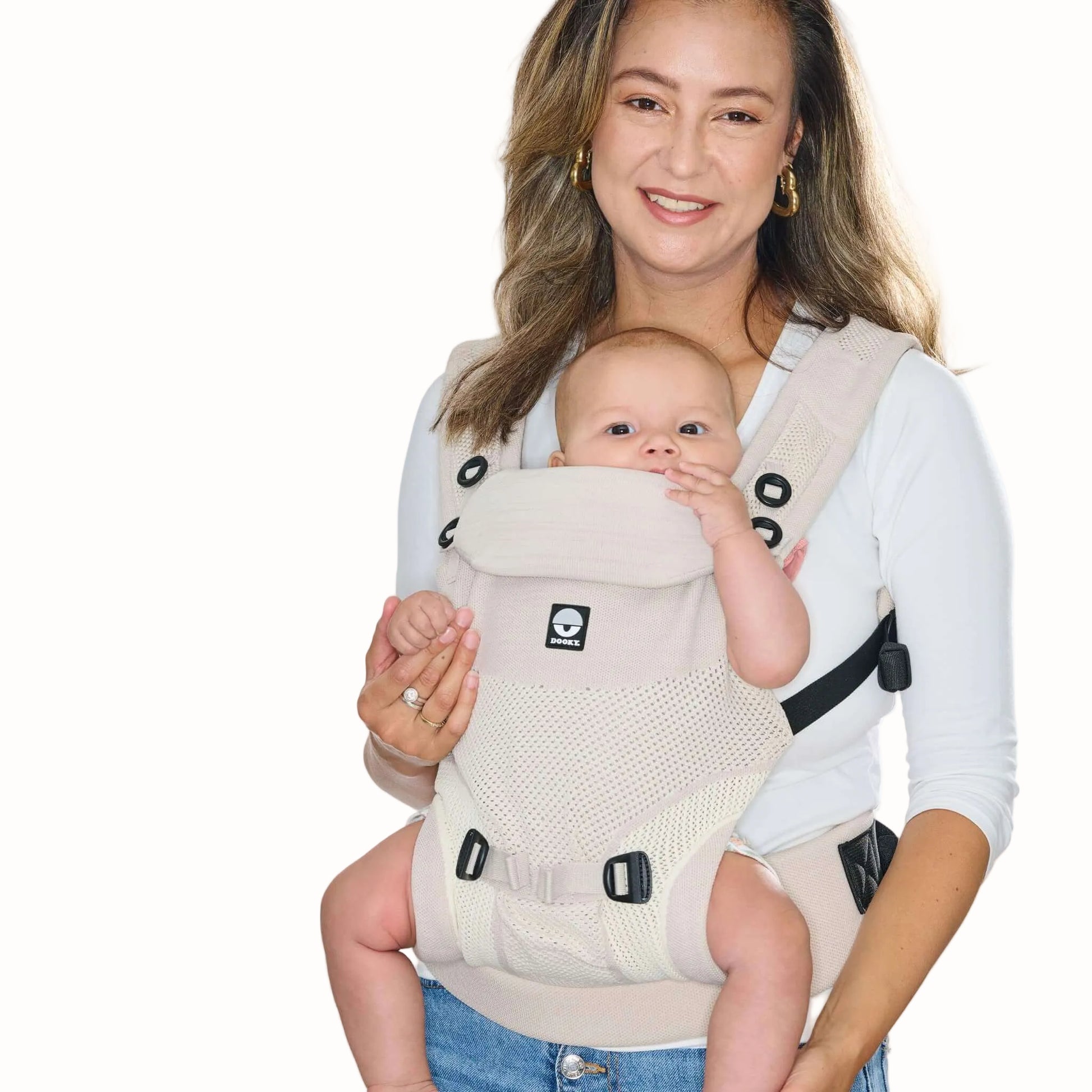 A baby carried facing outwards in a beige baby carrier, showing the supportive seat, shoulder straps and waist belt.